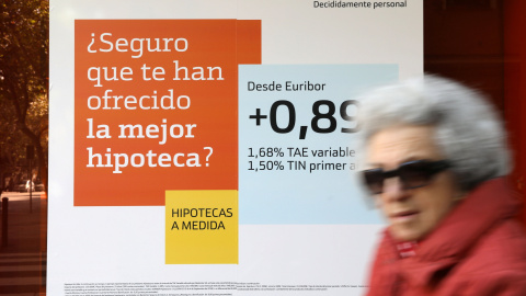 Una mujer pasa junto a una publicidad de hipotecas en una sucursal de Bankinter. REUTERS/Susana Vera