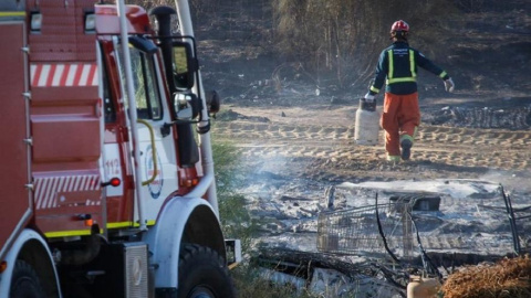 Un bombero trabaja en los restos de un incendio en un asentamiento chabolista de Lepe, en una imagen de archivo.