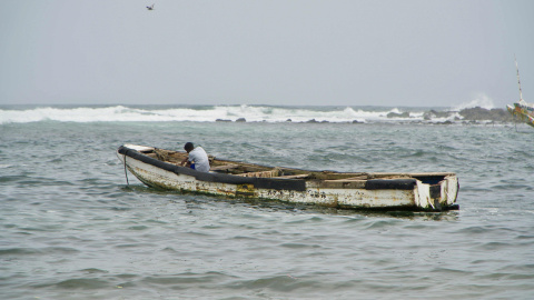 Niño sentado en una 'pirogue', mejor conocido como cayuco, en la playa de Yoff Thongor, Dakar