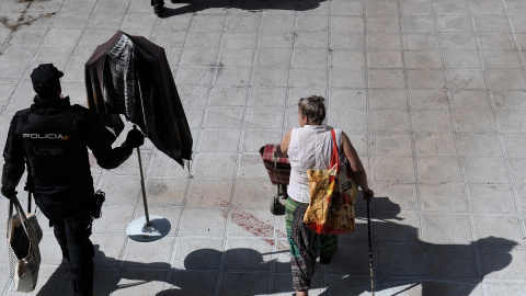 Una mujer tras ser desalojada del edificio Dignidad de Móstoles junto a un agente de Policía Nacional.