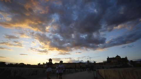 Varias personas caminan sobre el puente romano en Córdoba.