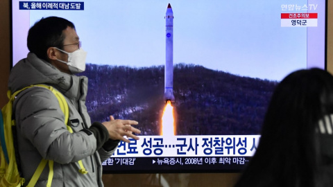 Un hombre frente a una televisión que muestra una transmisión de noticias con imágenes de archivo de una prueba de misiles de Corea del Norte el 31 de diciembre de 2022.