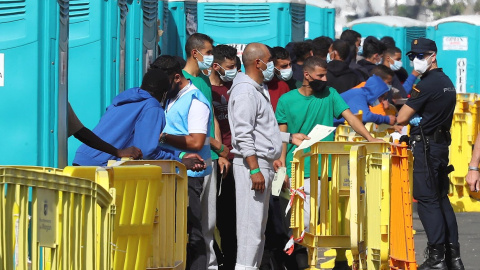 Varios migrantes esperan en el muelle de Arguineguín (Gran Canaria) a que les tomen las huellas dactilares y la filiación.