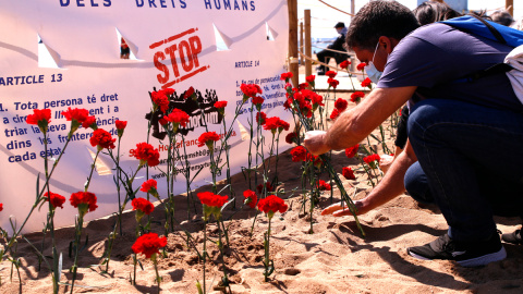 Un home plantant un clavell a la sorra de la platja. Imatge del 18 d'abril del 2021.