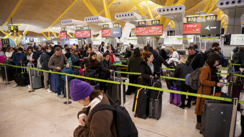 viajeros hacen cola ante los mostradores de 'check-in' de las compañías aéreas este viernes en el aeropuerto de Madrid Barajas.