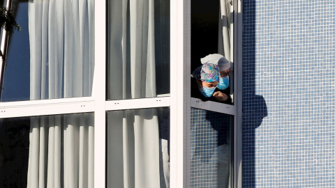 Dos mujeres se asoman a una ventana del geriátrico público de Laviana que alcanzó el viernes los 73 contagios y dos muertes de residentes.