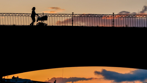 Una madre con un carrito de bebe paseando al atardecer por el Puente de Triana en Sevilla el 28 de abril del 2020.