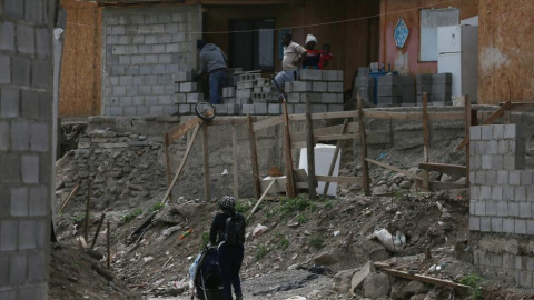 Haitianos cerca de una casa destruida.