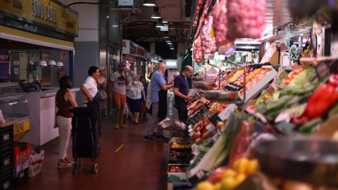 Varias personas hacen cola para hacer la compra en una frutería del Mercado de la Cebada, en Madrid.