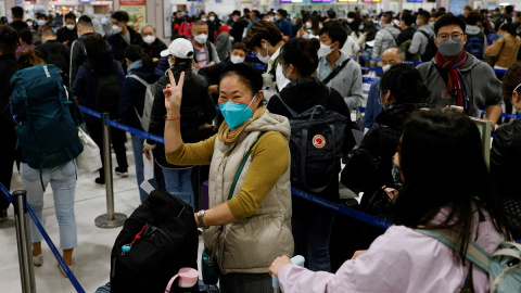 Una mujer celebra en una abarrotada estación de Lok Ma Chau, en Hong Kong, la reapertura de fronteras en China