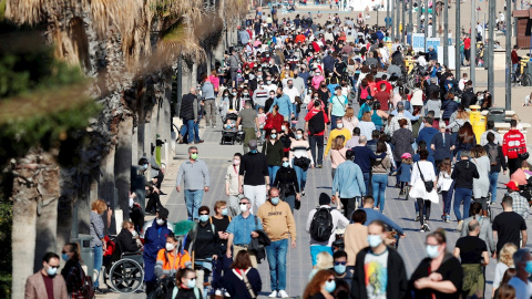 Fotografía de archivo de decenas de personas paseando por el paseo marítimo de playa de la Malvarrosa, en València.