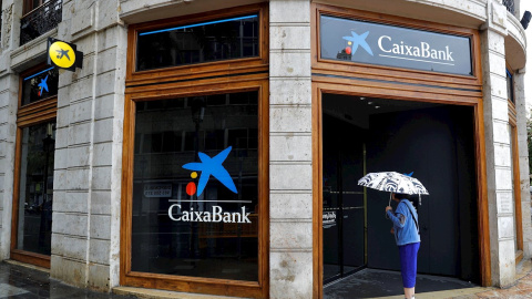 Una mujer observa el interior de la oficina de Caixabank en la plaza del Ayuntamiento de Valencia.  EFE/Manuel Bruque