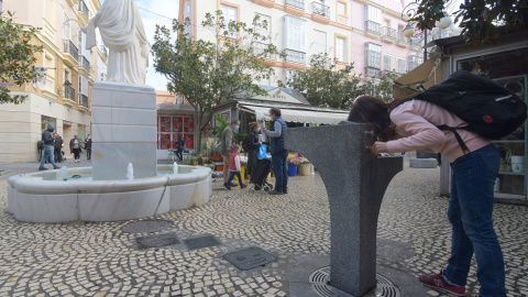 Una joven, bebiendo de una fuente pública en Cádiz.