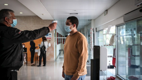 Personal de seguridad toma la temporada a un estudiante en la entrada de la facultad de Derecho de la Universidad de Lisboa.