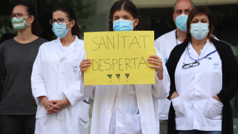 Una enfermera con una pancarta defendiendo la salud pública durante una movilización ante la Delegación de la Generalitat a Girona. ACN/Aleix Freixas