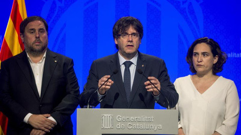 El presidente de la Generalitat, Carles Puigdemont (c), junto a la alcaldesa de Barcelona, Ada Colau (d), y el vicepresidente, Oriol Junqueras (i), hacen una declaración institucional para reprobar el atentado ocurrido esta tarde en Barcelona, un atropel