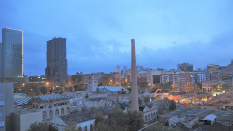 Les naus deteriorades de Can Ricart amb la seva gran xemeneia en peu, mentre al seu voltant es construeixen oficines i hotels.