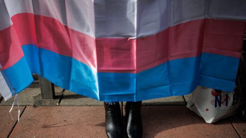 Los zapatos de una mujer debajo de una bandera trans durante una concentración de la Federación Plataforma Trans, a 28 de octubre de 2022, en Madrid.