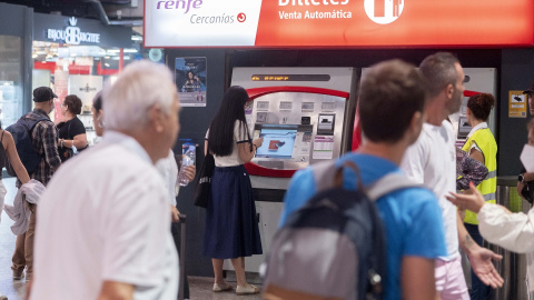 Varias personas adquieren sus billetes en las taquillas de venta automática de la estación de tren de Atocha.