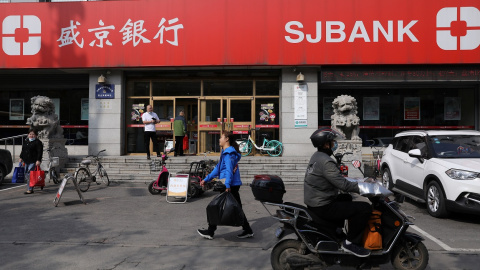 Varias personas pasan por delante de una sucursar del banco chono Shengjing Bank, en la localidad de Shenyang (provincia de Liaoning). REUTERS/Tingshu Wang