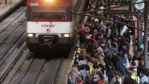 Un gran número de pasajeros espera la llegada de un tren en la estación de Madrid.