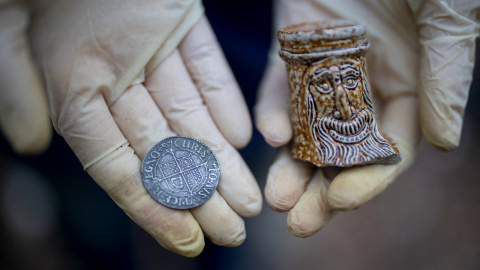 Lara Maiklem, autora del libro ‘Mudlarking’, muestra una moneda del siglo XVII y un trozo de una belarmina en el río Támesis de Londres.