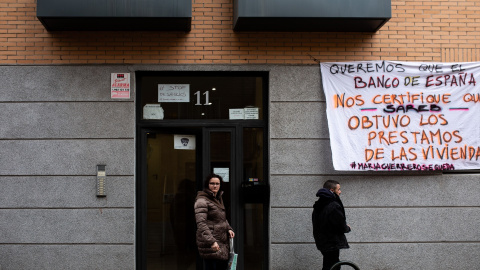 Varias personas pasan por la fachada del número 11 de la calle María Guerrero del madrileño barrio de Carabanchel donde hay un cartel contra la Sareb. Imagen de archivo.