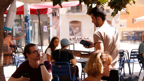 09/08/2024 - Un cambrer en una terrassa d'un bar de Gràcia, a Barcelona.