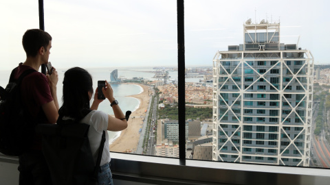 Dos visitants fotografien l'hotel Arts des de la torre Mapfre en el 48H Open House en una imatge d'arxiu