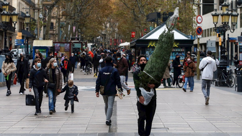 Una persona transporta un árbol de navidad por las Ramblas de Barcelona.