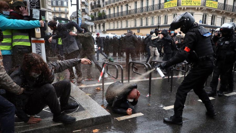 Un agente de policía francés echa spray sobre un manifestante en el suelo.