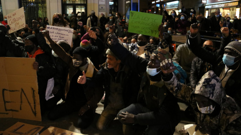 Persones assegudes i amb el puny alçat durant el minut de silenci a la Plaça de la Vila de Badalona.