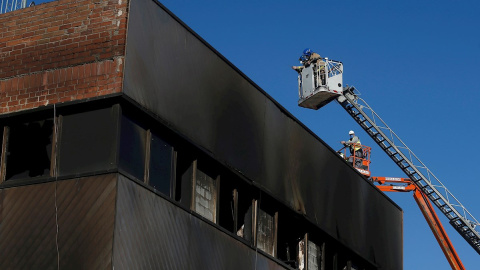 Bomberos de la Generalitat de Catalunya y trabajadores de la empresa de derribos inspeccionan este sábado en Badalona el inicio de la demolición de la nave donde murieron tres inmigrantes "sin techo" en un incendio. La nave, una antigua fábrica en desu