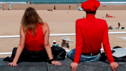 Dos personas disfrutan de las vistas de la playa en San Sebastián.