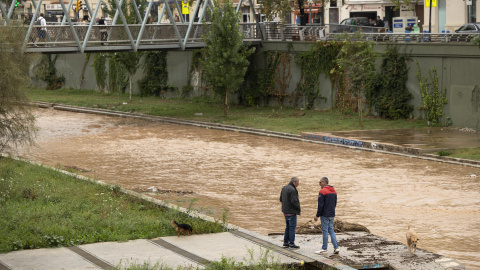 Varias personas observan el río Guadalmedina a su paso por Málaga capital que se encuentra cubierto de agua por las fuertes lluvias, a 29 de octubre de 2024.