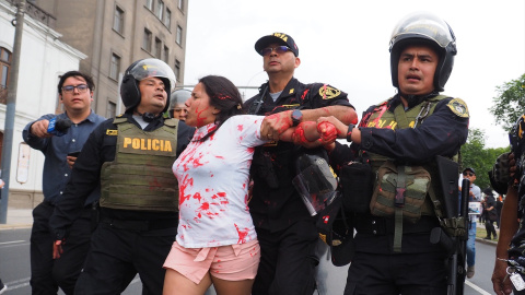 Policías antidisturbios arrestan a una mujer luego de arrojar pintura roja a policías cuando cientos marchan por la paz en Lima y las principales ciudades del país luego de los disturbios de diciembre pasado contra el actual gobierno de Dina Boluarte y