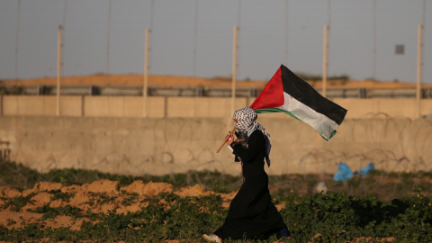 Una mujer con la bandera palestina en una protesta contra Israel en la frontera con Gaza. REUTERS/Ibraheem Abu Mustafa