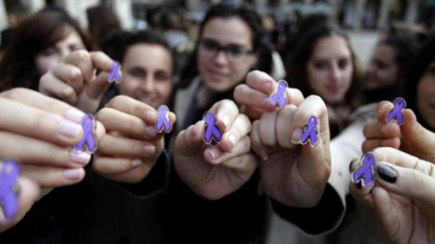 Un grupo de jóvenes muestran pines con lazos morados contra la violencia machista. EFE/Archivo