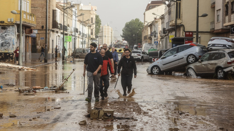 Varias personas recorren calles llenas de agua y barro tras el paso de la DANA por el barrio de La Torre de València, a 30 de octubre de 2024.