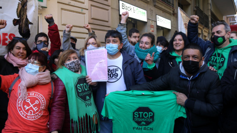 El Carlos, envoltat d'activistes pel dret a l'habitatge, mostrant el paper de suspensió del desnonament que l'afectava, aquest 3 de desembre de 2021.