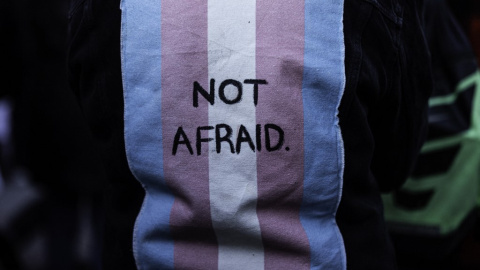 Imagen de archivo de una persona con un chaleco con una bandera trans en la espalda con las palabras "Sin miedo"