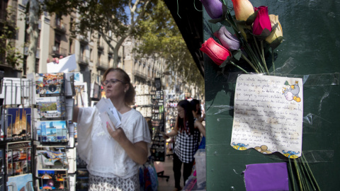 Una carta dedicada a unas de las víctimas de un ciudadano que ayudó a las víctimas del atentado pegada en una pared de un kiosko donde varios turistas compran postales en las Ramblas de Barcelona. EFE/Marta Pérez