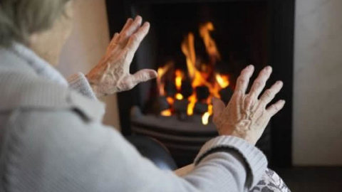 Una mujer calienta sus manos en una chimenea.