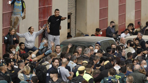 El rey Felipe (c) rodeado por vecinos indignados, durante su visita a Paiporta este domingo. Gritos de 'fuera', así como lanzamiento de barro, están recibiendo a la comitiva de los reyes de España, el presidente del Gobierno, Pedro Sánchez, y el presi