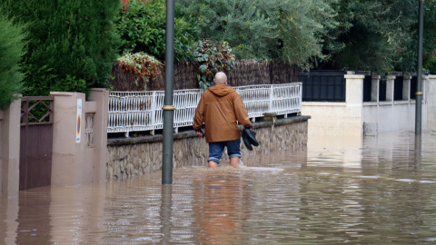 Un home caminant per un carrer inundat de la urbanització La Móra de Tarragona