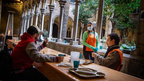 Voluntaris i un usuari del menjador de Santa Anna parlen a l'hora de dinar.