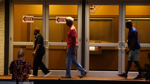 Los trabajadores electorales cuelgan carteles que dicen "votar" en las puertas antes de que se abran las urnas el día de las elecciones en el Coliseo de San Petersburgo, a 5 de noviembre de 2024.