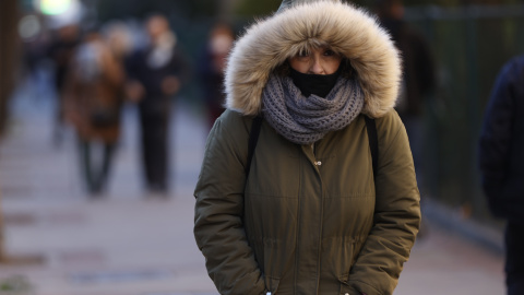 Una mujer pasea por Madrid cuando la capital se encuentra en aviso amarillo por temperaturas mínimas.