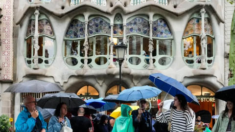 Persones es protegeixen de la pluja al passeig de Gràcia de Barcelona, en una imatge d'arxiu