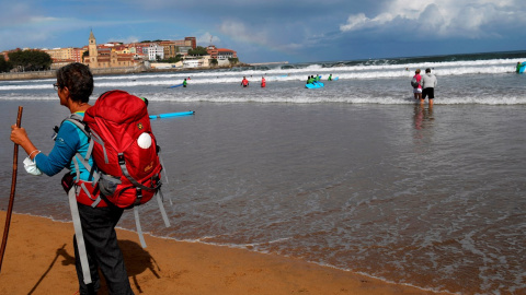 Una mujer pasea por la playa de San Lorenzo de Gijón.